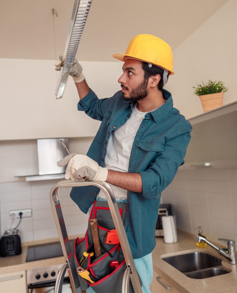 Electrician worker is installing electric lamps light in kitchen. Construction decoration concept